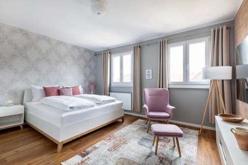 a bedroom with a white bed and a pink chair at PRIMERA Zimmer mit Gemeinschaftsbad in Singen