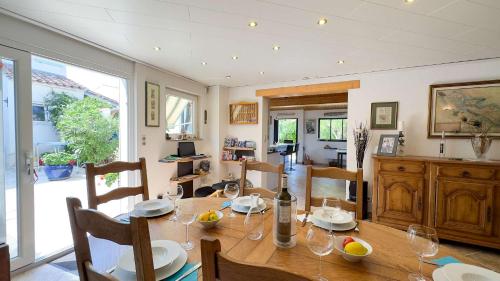 une salle à manger avec une table en bois et des verres à vin dans l'établissement Charmante location en 2 parties dans le village de Loix, à Loix