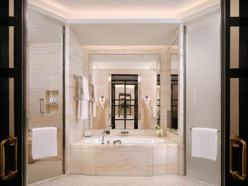 uma casa de banho com uma banheira e um espelho grande em The Peninsula London em Londres