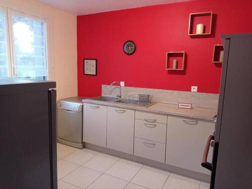 eine Küche mit einem Waschbecken und einer roten Wand in der Unterkunft Maison au calme avec jardin et local vélo in Jonquières