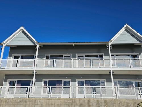 a house with white balconies and a blue sky at Bahia Rooms in El Calafate