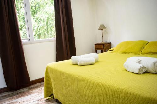 a bedroom with a yellow bed with towels on it at Bahia Rooms in El Calafate