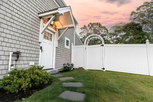 a white fence in front of a house at Renovated & Sophisticated Home Near Beach & Shops! in Barnstable
