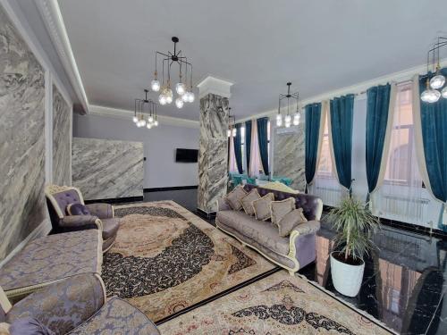 een woonkamer met een bank, stoelen en ramen bij Гостиница-хостел Дастур 