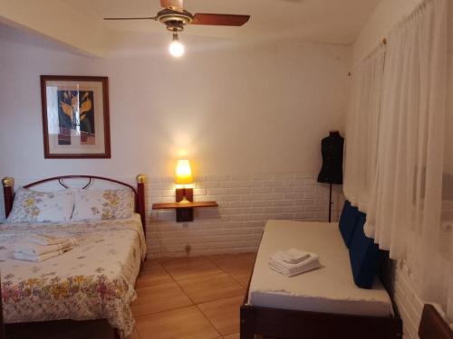 a bedroom with a bed and a table and a lamp at Cantinho da Vovó Regina in Miguel Pereira