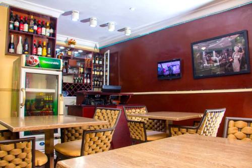 a restaurant with tables and chairs and a tv on the wall at ERiTH APARTMENT & SUITES in Ikeja