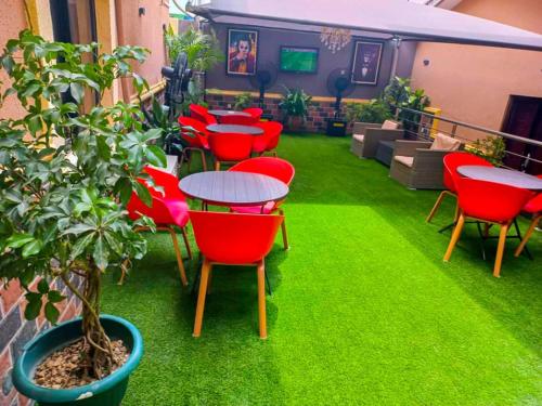 a patio with red chairs and tables and a plant at ERiTH APARTMENT & SUITES in Ikeja