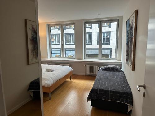 a bedroom with a bed and two windows at 2 Bedroom Apartment in Lovely Louise Area in Brussels