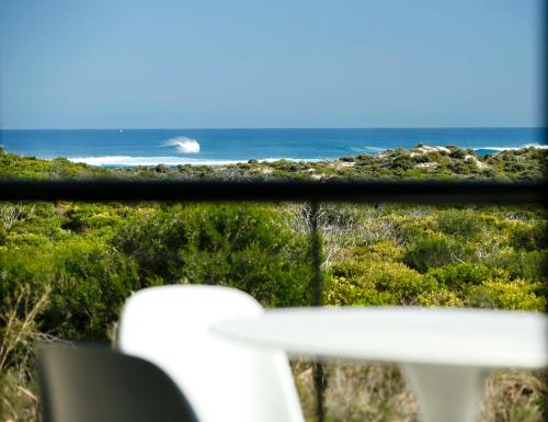 a view of the ocean from a window with a chair at Panorama at Margarets Beach in Gnarabup
