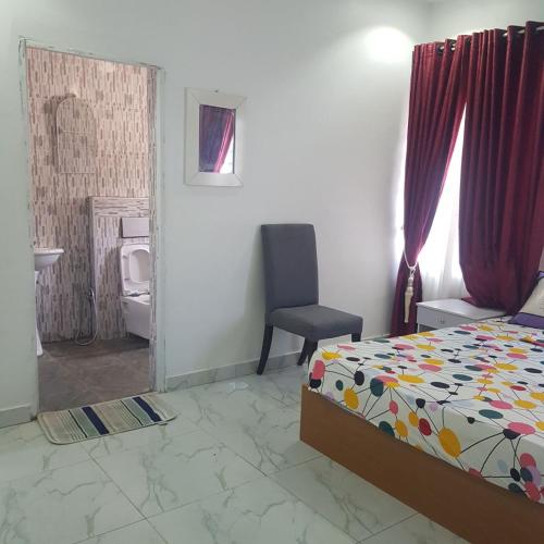 um quarto com uma cama e uma cadeira em SURPRISE PALACE em Ibadan