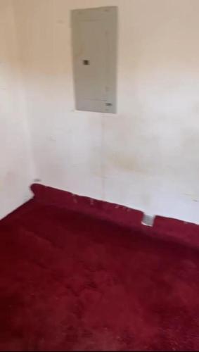 uma cama vermelha com uma parede branca e uma ventilação em غرفة سائق للايجار مؤثثه مكيف و مفروشة ثلاجة وسرير em Riyadh