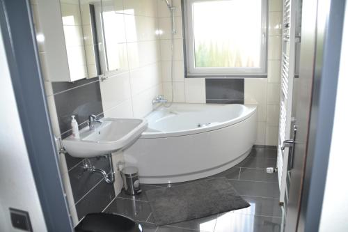 baño con bañera, lavabo y ventana en Ferienwohnung Am Steinberg, en Hildesheim