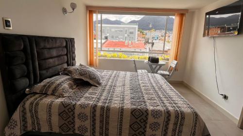 um quarto com uma cama e uma grande janela em Apartamento movistar Arena-Estadio El Campin-galerías con garaje 2 a 6 personas em Bogotá