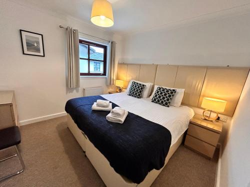 a bedroom with a large bed with two towels on it at Principal Apartments - Merchant City in Glasgow