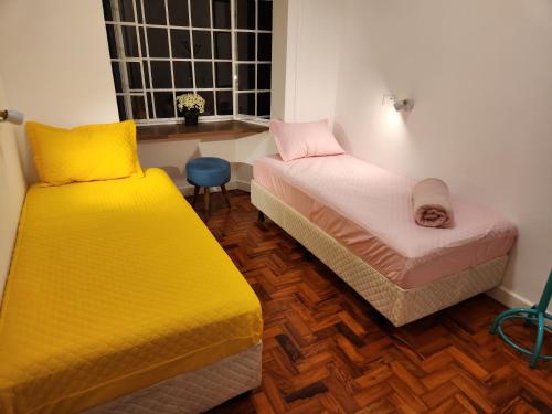 a room with two beds with yellow and pink at Morada City Hostel in Sao Paulo