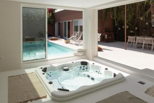 a jacuzzi tub in the middle of a room with windows at Casa dos Pinheiros 109 - Private Villa with pool & heated SPA in Porto