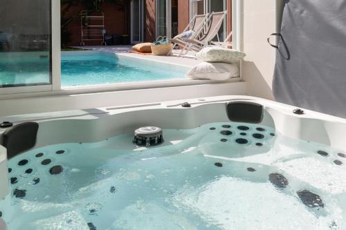 uma banheira de hidromassagem em frente a uma piscina em Casa dos Pinheiros 109 - Private Villa with pool & heated SPA no Porto