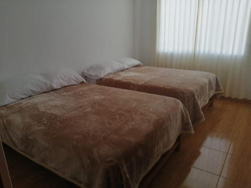 two beds with brown covers in a room at Apartamentos Cristo Rey. in Tacna