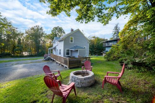 four red chairs sitting around a fire pit in front of a house at Catskill's Cozy Farmhouse Getaway in Gilboa