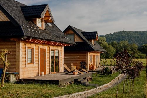 une cabane en rondins avec une terrasse couverte et une maison dans l'établissement "Polne Domki" Osada Drewniana w Harklowej, à Harklowa