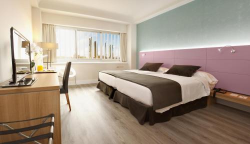 a bedroom with a large bed and a desk with a television at Hotel Chamartin The One in Madrid