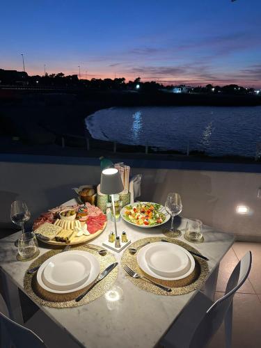 a table with plates of food and wine glasses at Torre Pozzillo Beach in Cinisi