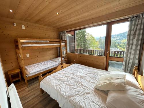 - une chambre dans une cabane en rondins avec un lit et une fenêtre dans l'établissement Les Gets - Appartement rénové proche pistes, navette gratuite, parking - FR-1-623-114, aux Gets