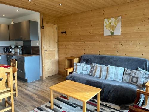 un salon avec un canapé bleu et une cuisine dans l'établissement Les Gets - Appartement rénové proche pistes, navette gratuite, parking - FR-1-623-114, aux Gets