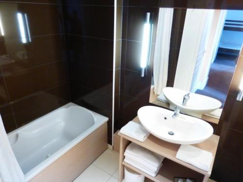 a bathroom with a sink and a tub and a toilet and a sink at Appartement Standing Château des Magnans in Jausiers