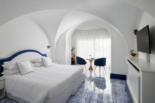 a white bedroom with a bed and a table and chairs at Hotel Scalinatella in Capri