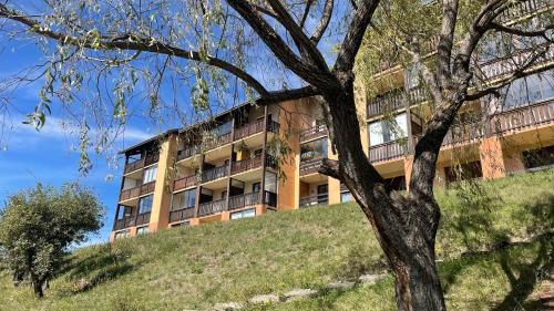 an apartment building on top of a hill with a tree at La Méa in Barcelonnette
