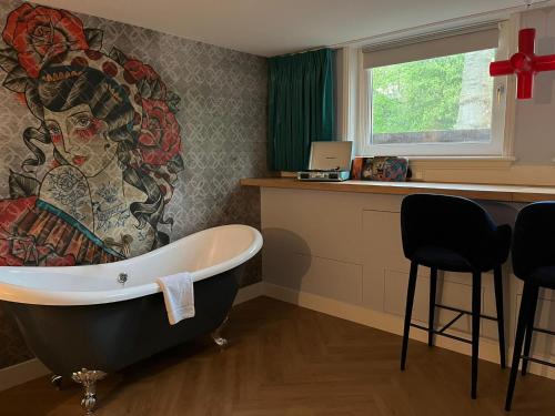 a bath tub in a bathroom with a painting on the wall at MUZE Hotel Utrecht in Utrecht