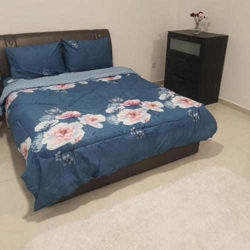un letto con un piumone blu e fiori rosa di D Laman Haris Homestay a Bandar Puncak Alam
