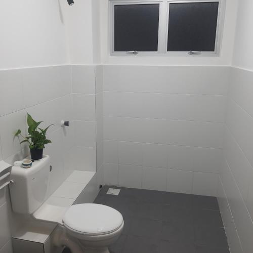 biała łazienka z toaletą i oknem w obiekcie D Laman Haris Homestay w mieście Bandar Puncak Alam