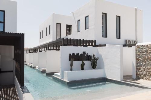 a pool with blue water in front of a white building at Laguna Suites in Mazera Mykonos in Mýkonos City