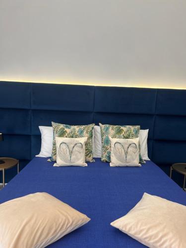 un letto blu con cuscini bianchi e testiera blu di Aries Suite Pompei a Pompei