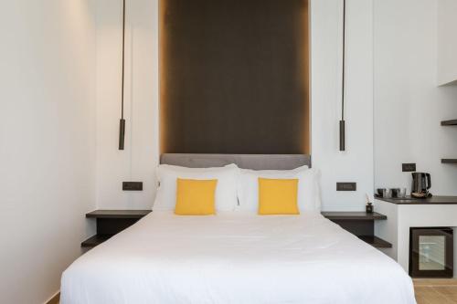 a bedroom with a white bed with two yellow pillows at Laguna Suites in Mazera Mykonos in Mýkonos City