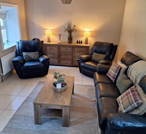a living room with leather couches and a coffee table at White Mountain Cottage in Newry