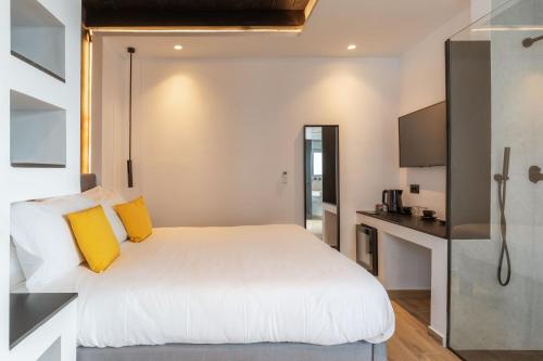 a bedroom with a large white bed with yellow pillows at Laguna Suites in Mazera Mykonos in Mýkonos City