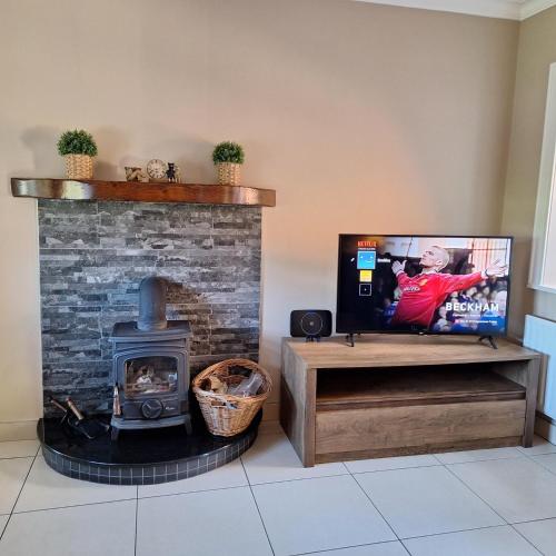 a living room with a fireplace and a flat screen tv at White Mountain Cottage in Newry