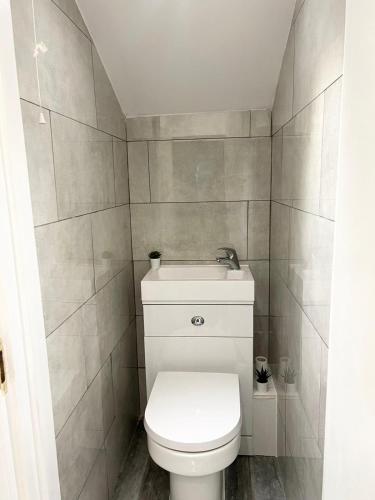 a bathroom with a white toilet and tiled walls at Cosy Stunning Flat in London