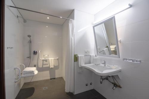 een witte badkamer met een wastafel en een spiegel bij Hilton Garden Inn Montevideo in Montevideo