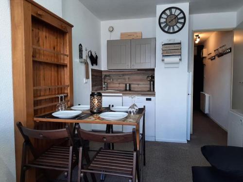 a kitchen with a table and chairs and a clock on the wall at Appartement vue panoramique au pied des pistes in La Ferrière
