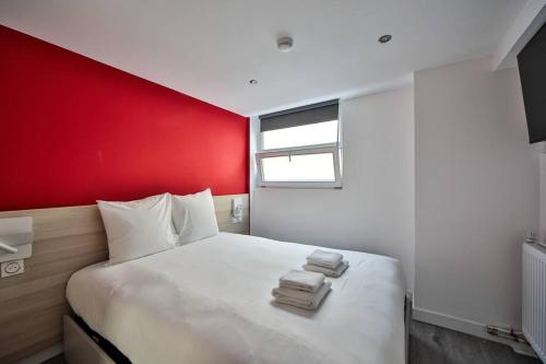 1 dormitorio con cama blanca y pared roja en 05.Studio#Charenton#Fitness#Cinema, en Charenton-le-Pont