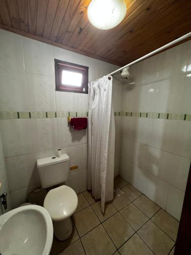 uma casa de banho com um WC, um lavatório e uma janela em Cabañas La Delfina em Puerto Iguazú