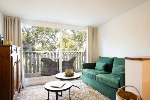 a living room with a green couch and a balcony at Hôtel Font Mourier in Cogolin