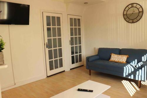 a living room with a blue couch and a clock on the wall at Stunning Guest House FREE WiFi &Parking in Hunslet
