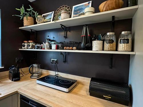 a kitchen with a counter with a stove and shelves at Luxury Croft Templepatrick Near Airport Rabbit and Hilton hotel in Templepatrick