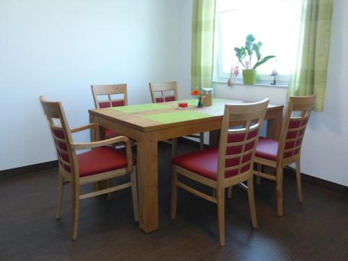 a wooden table with four chairs and a table and a window at Pension Augenblick in Greifswald
