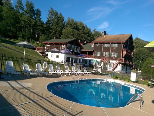 a swimming pool in front of a large house at Swiss Chalets Village Inn in North Conway
